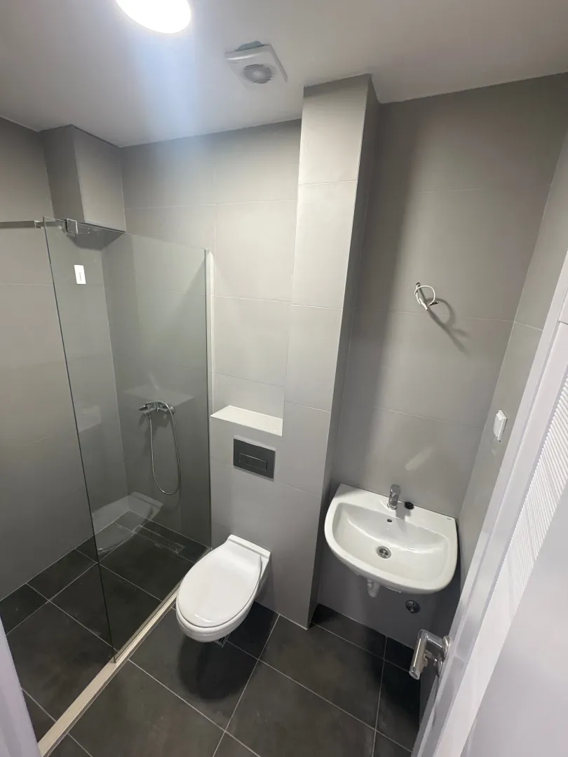 Moderne kupatilo sa tuš kabinom, umivaonikom i WC šoljom.
