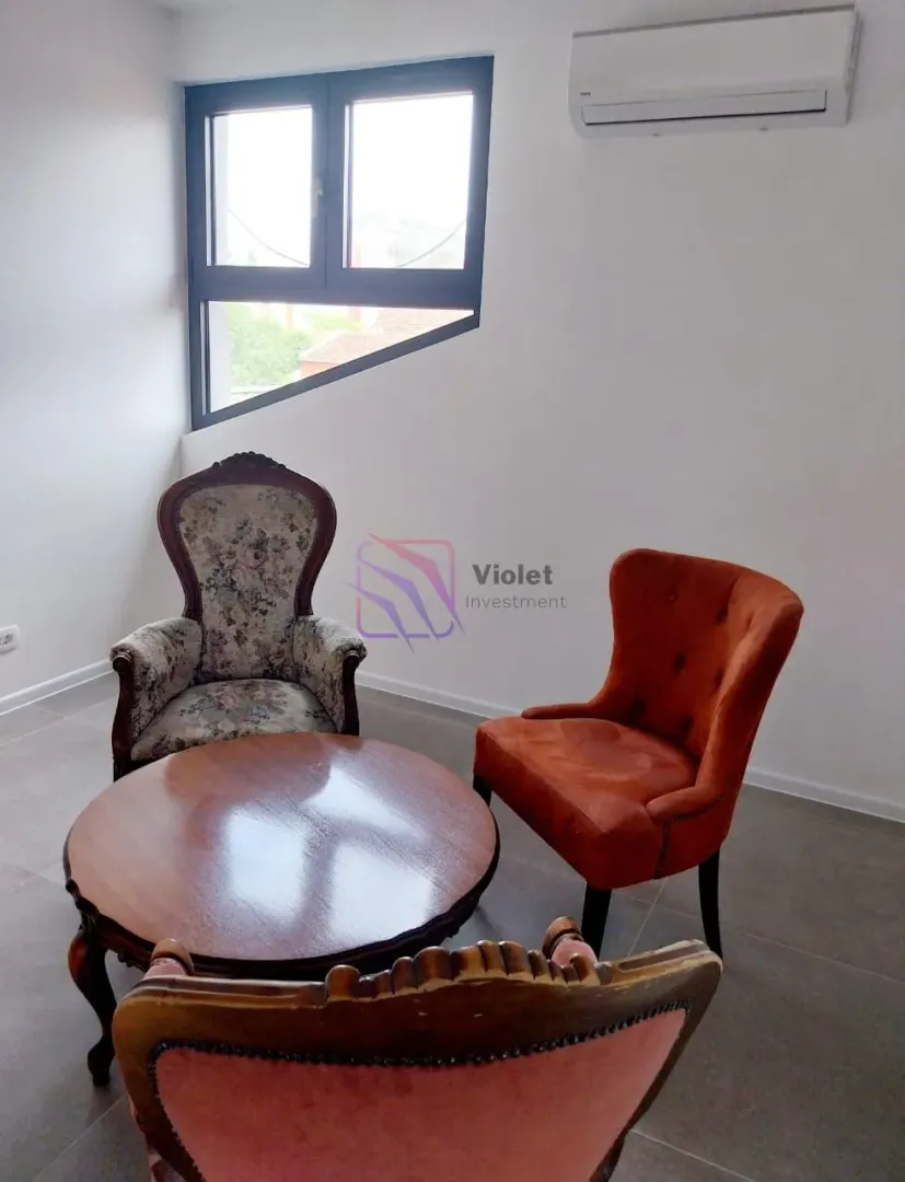 Living room with seating furniture and an unusually shaped window.