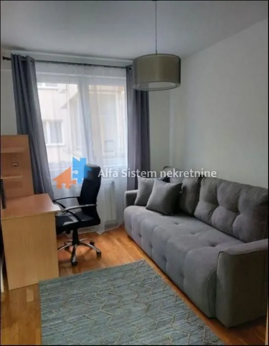 Living room with a grey sofa, office desk and chair.