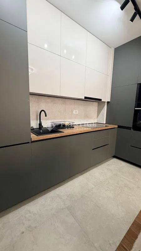 Modern kitchen with dark cabinets and white upper units.