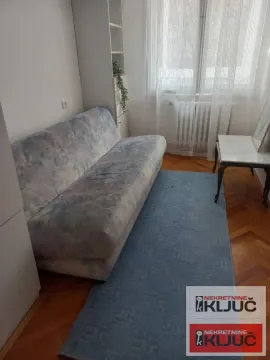Manji dnevni boravak sa trosedom, tepihom i prozorom sa belim zavesama. - image 9