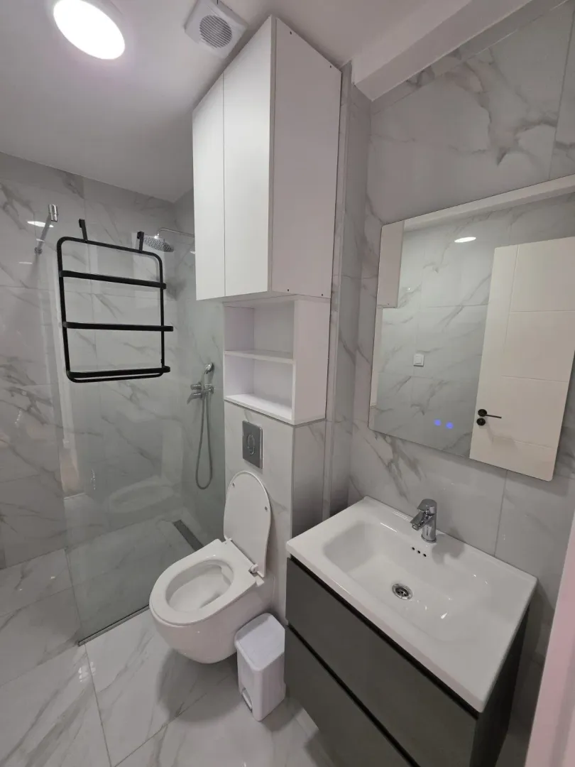 Modern bathroom with a walk-in shower, toilet, and vanity unit.