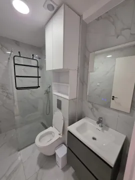 Modern bathroom with a walk-in shower, toilet, and vanity unit. - image 10