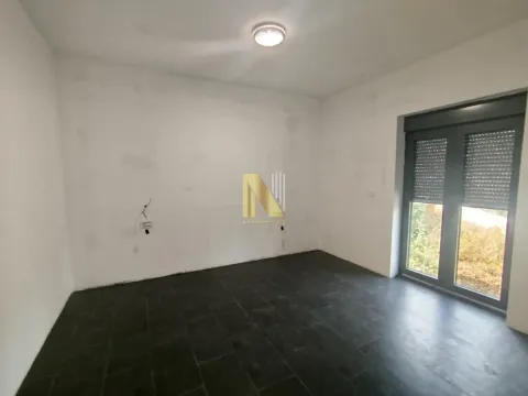 Prazna neuređena prostorija sa tamnim pločicama na podu i vratima sa roletnama. - image 16