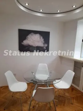 Trpezarija sa okruglim staklenim stolom i belim stolicama. - image 11