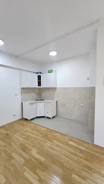 Smaller white kitchen within a room with parquet flooring. - image 2