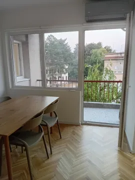 Trpezarija sa drvenim stolom i stolicama pored balkonskih vrata. - image 2