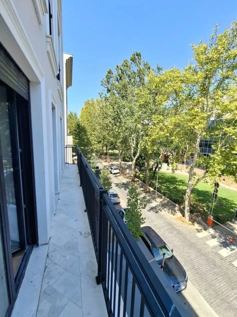 Dugačak balkon sa pogledom na ulicu i drveće.