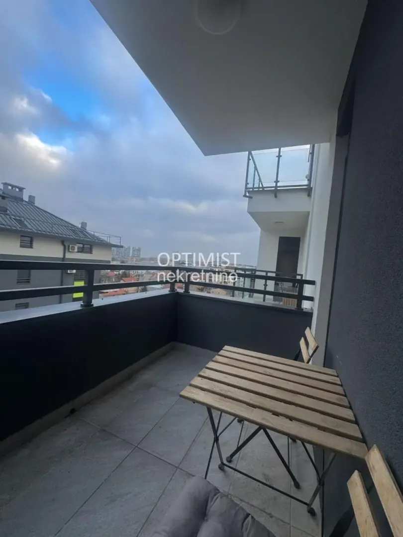 Natkriveni balkon sa stolom i pogledom na grad.