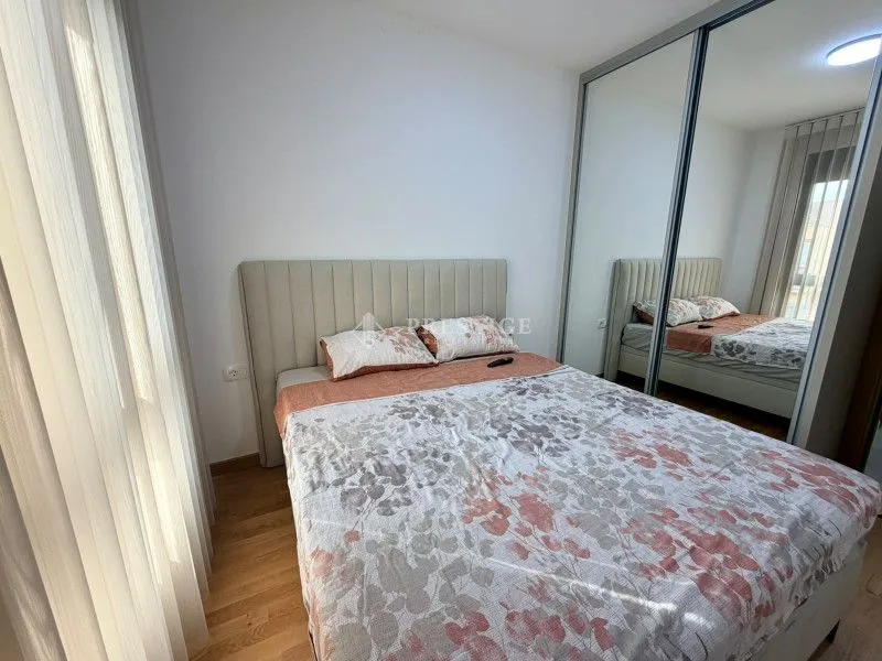 Spavaća soba sa bračnim krevetom i velikim plakarom sa ogledalom.
