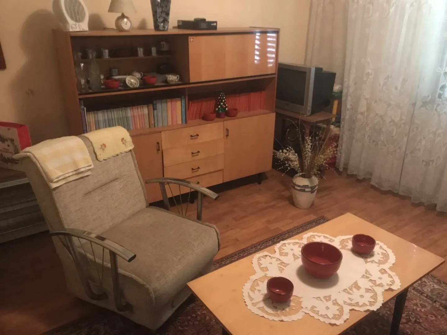 Dnevna soba sa retro namještajem, foteljom i drvenim stolom.