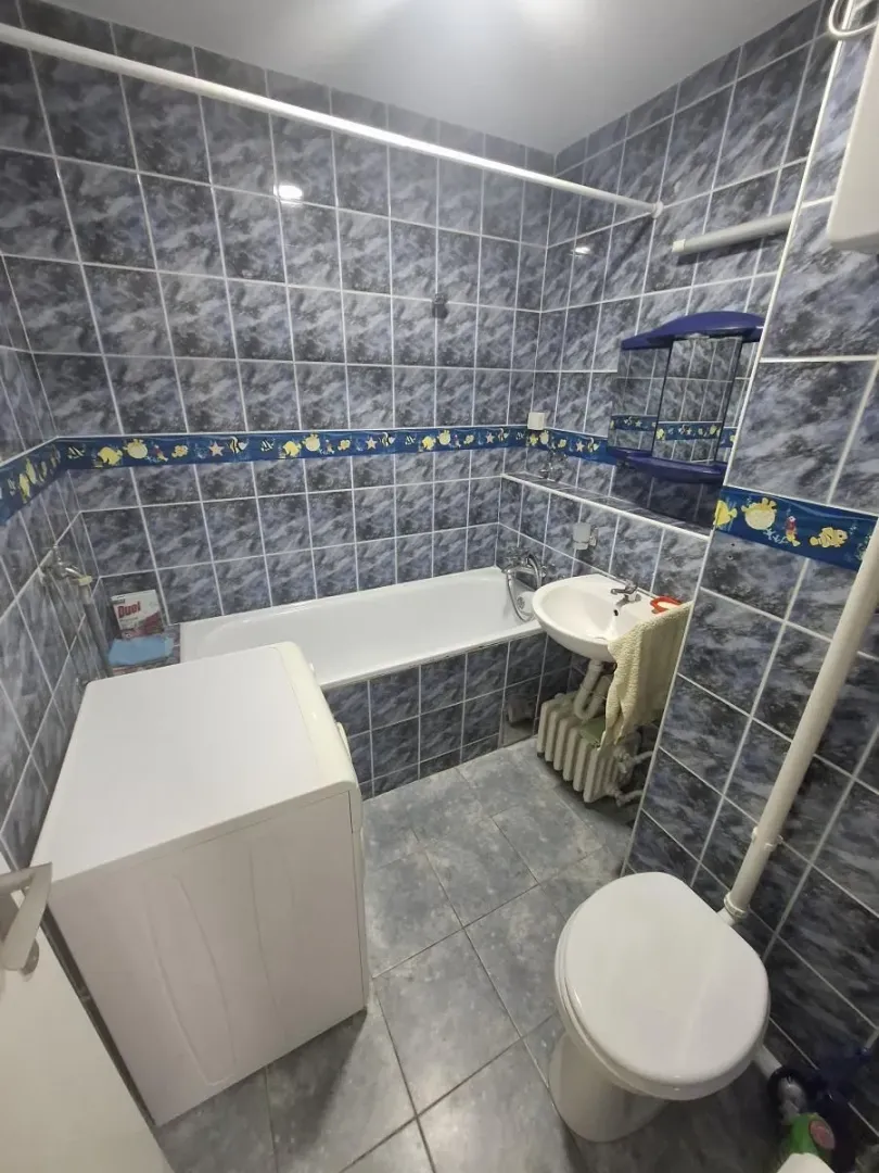Tiled bathroom with a bathtub, washbasin, toilet, and washing machine.