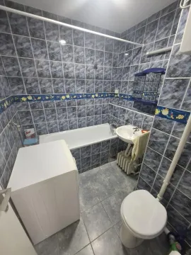 Tiled bathroom with a bathtub, washbasin, toilet, and washing machine. - image 9