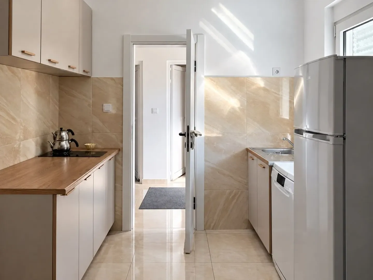 Small modern kitchen with beige cabinets and built-in appliances.