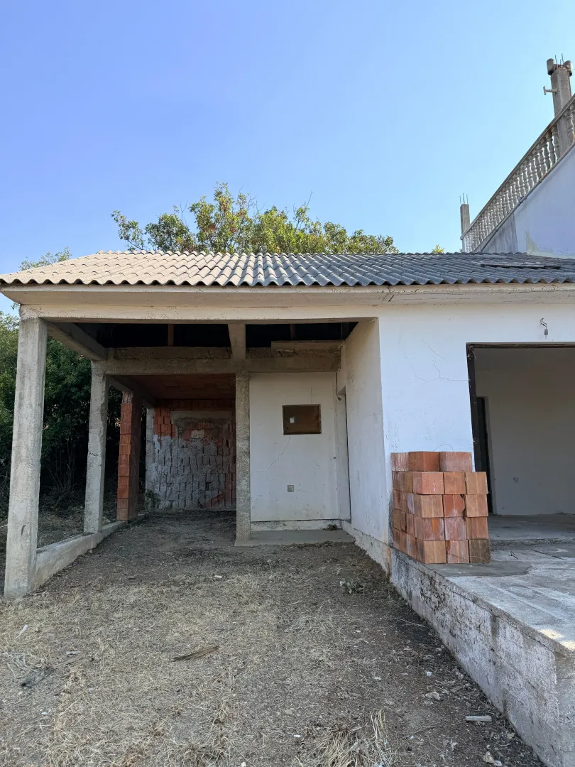 Exterior of a house under construction with a covered area and building materials.