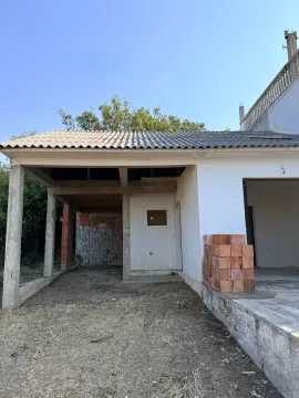 Exterior of a house under construction with a covered area and building materials. - image 11