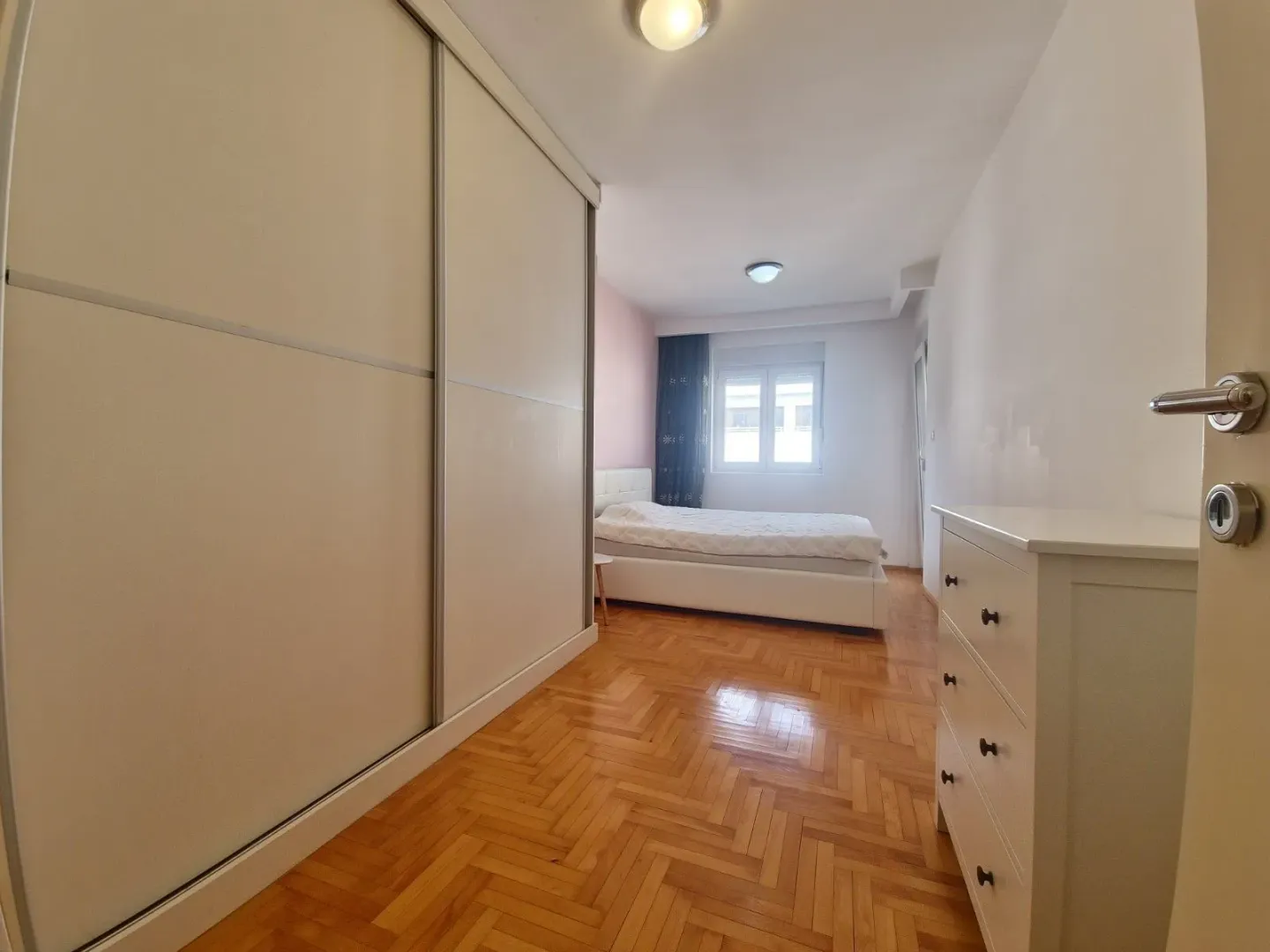 Bedroom with a large built-in wardrobe, bed, and chest of drawers.