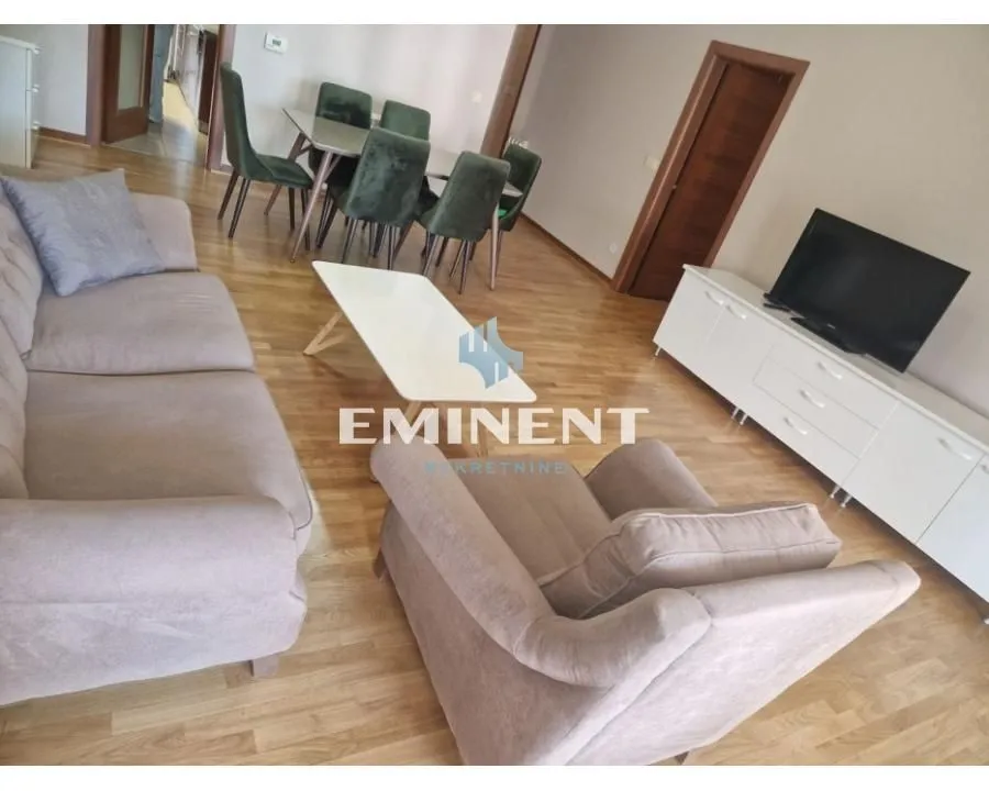Living room with a sofa set, TV unit, and dining table.