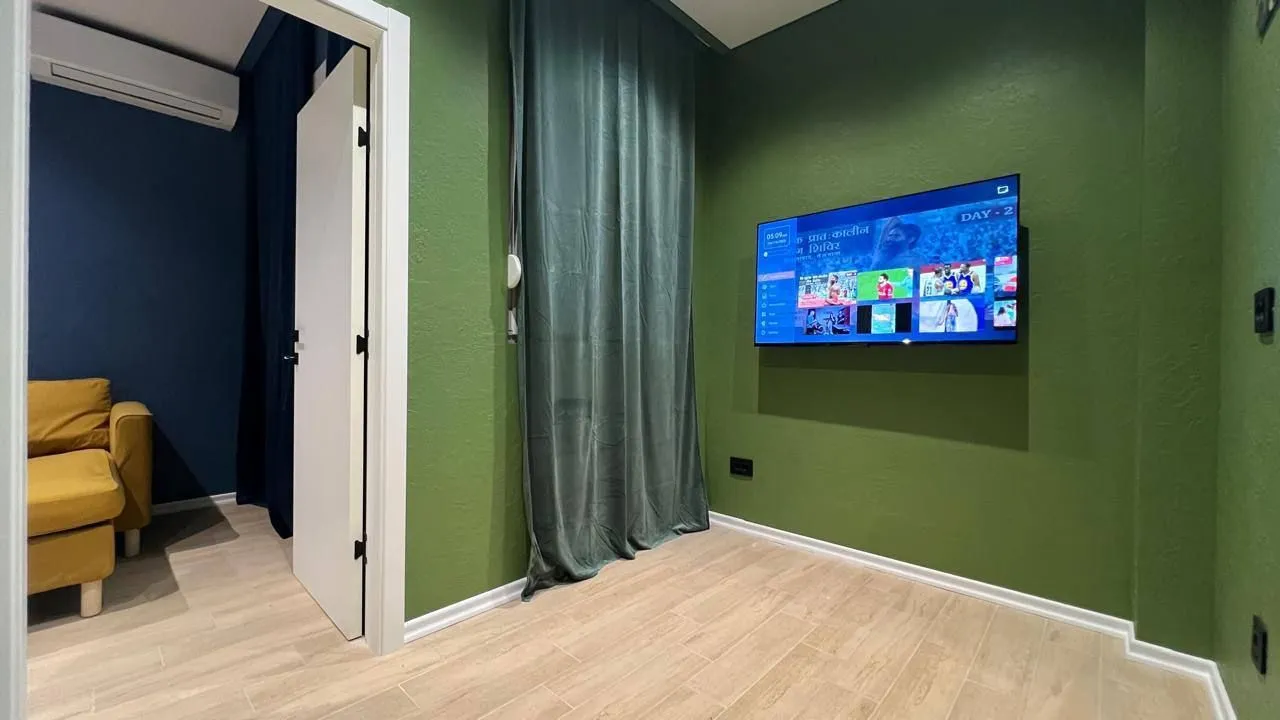 Dnevna soba sa zelenim zidovima i televizorom.