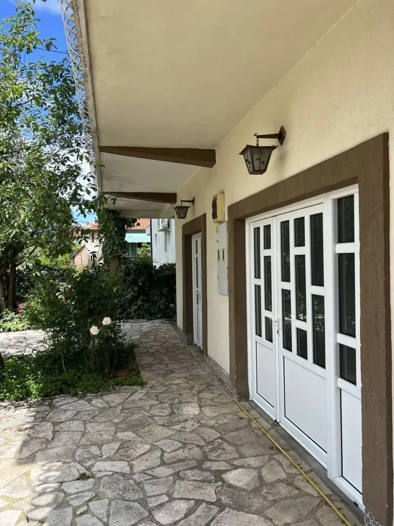 Covered porch and paved yard in front of the house entrance.
