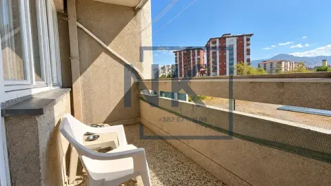 Manji balkon sa plastičnim stolicama i pogledom na okolne zgrade i brda. - image 15