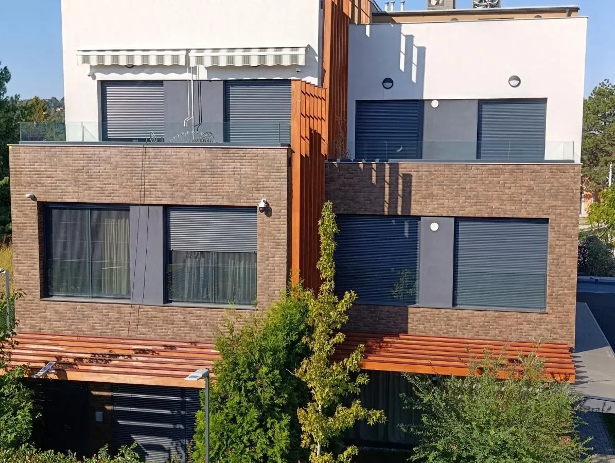 Exterior view of a modern residential building with a balcony and landscaped yard.