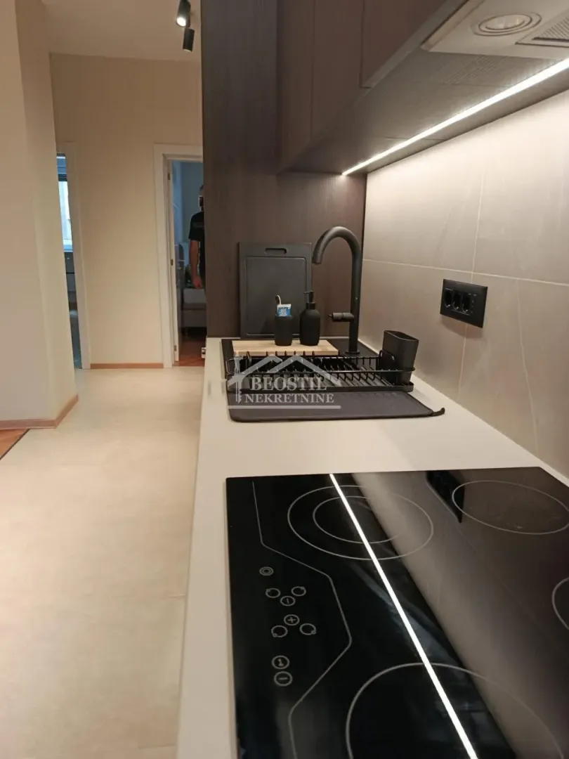 Pogled na moderno opremljenu kuhinju sa ugrađenom pločom za kuvanje i sudoperom.