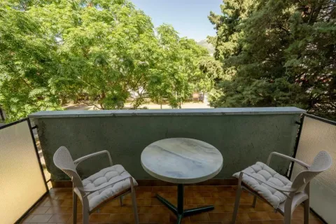 Furnished balcony with a table and two chairs and a view of greenery. - image 8