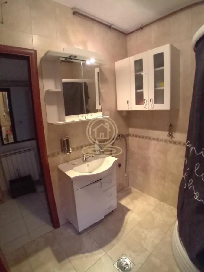Kupatilo opremljeno umivaonikom, ogledalom i zidnim ormarićem.
