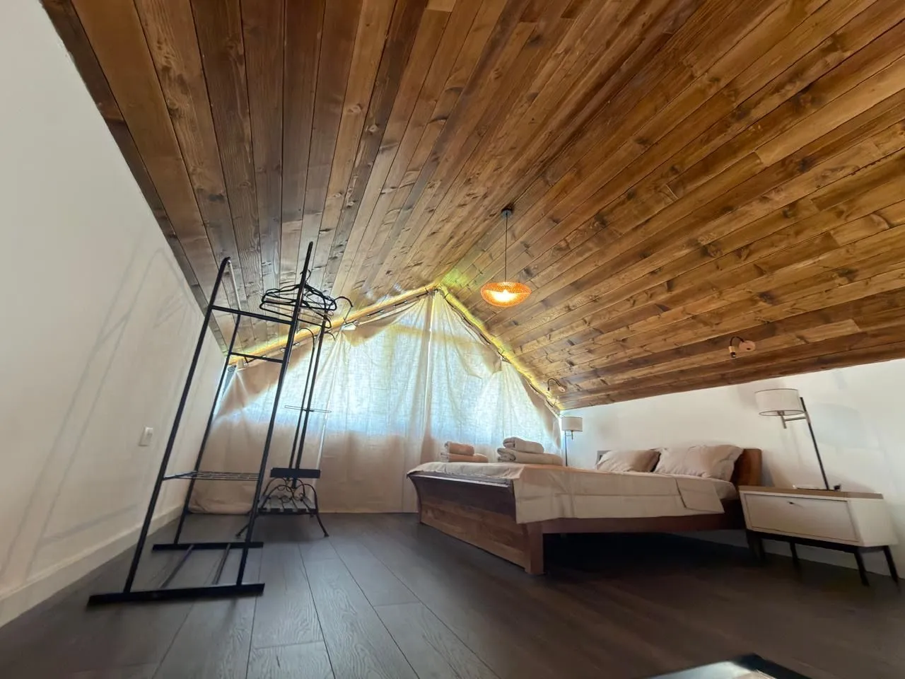 Attic bedroom with wooden ceiling and a double bed.