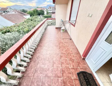 Dugački popločani balkon sa ogradom i pogledom na okolno naselje. - image 13