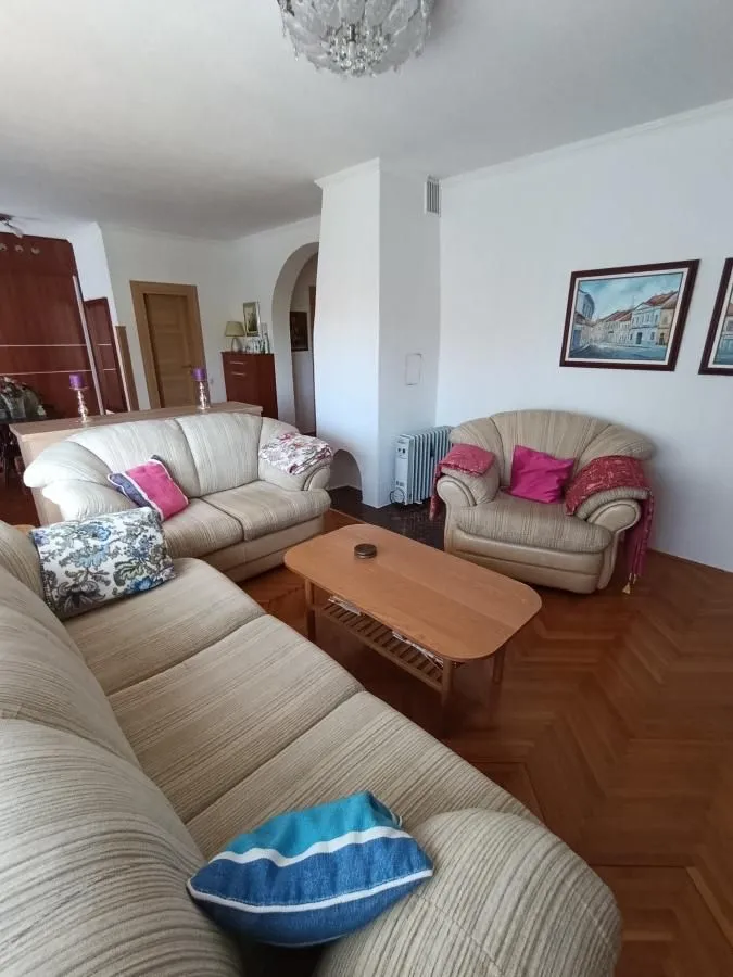 Dnevna soba sa garniturom za sedenje i drvenim podom.