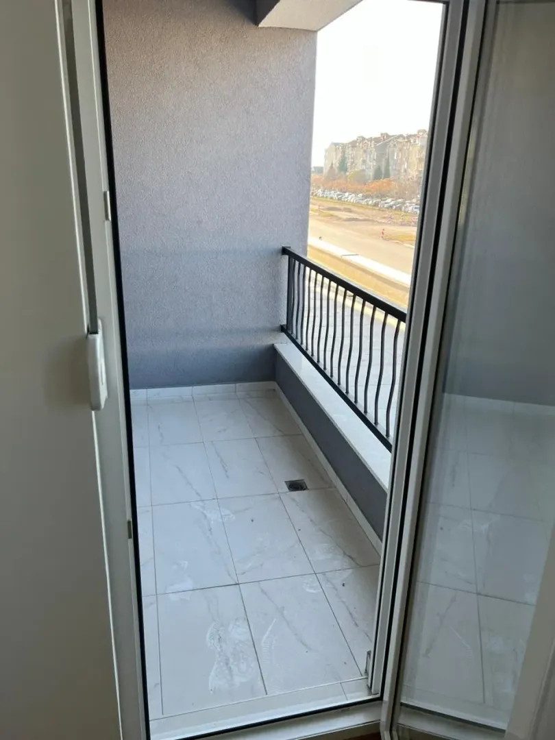Empty balcony with light tiles and a railing.