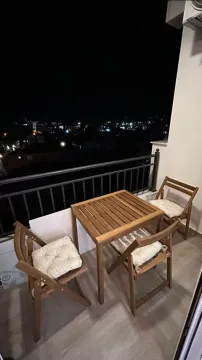 Furnished balcony with seating and a night view of the city. - image 8
