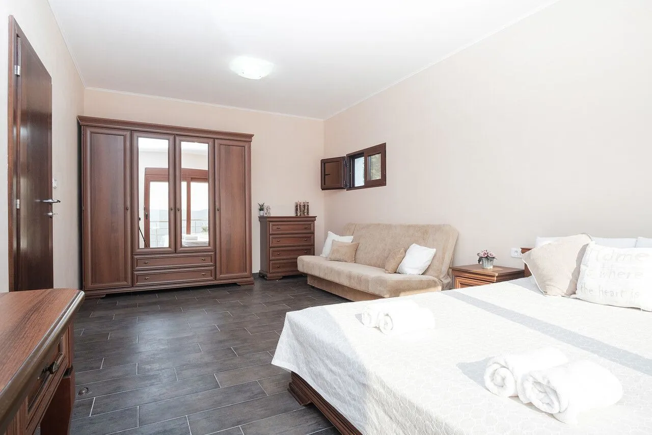 Spacious bedroom with a double bed, wardrobe, and a sofa.