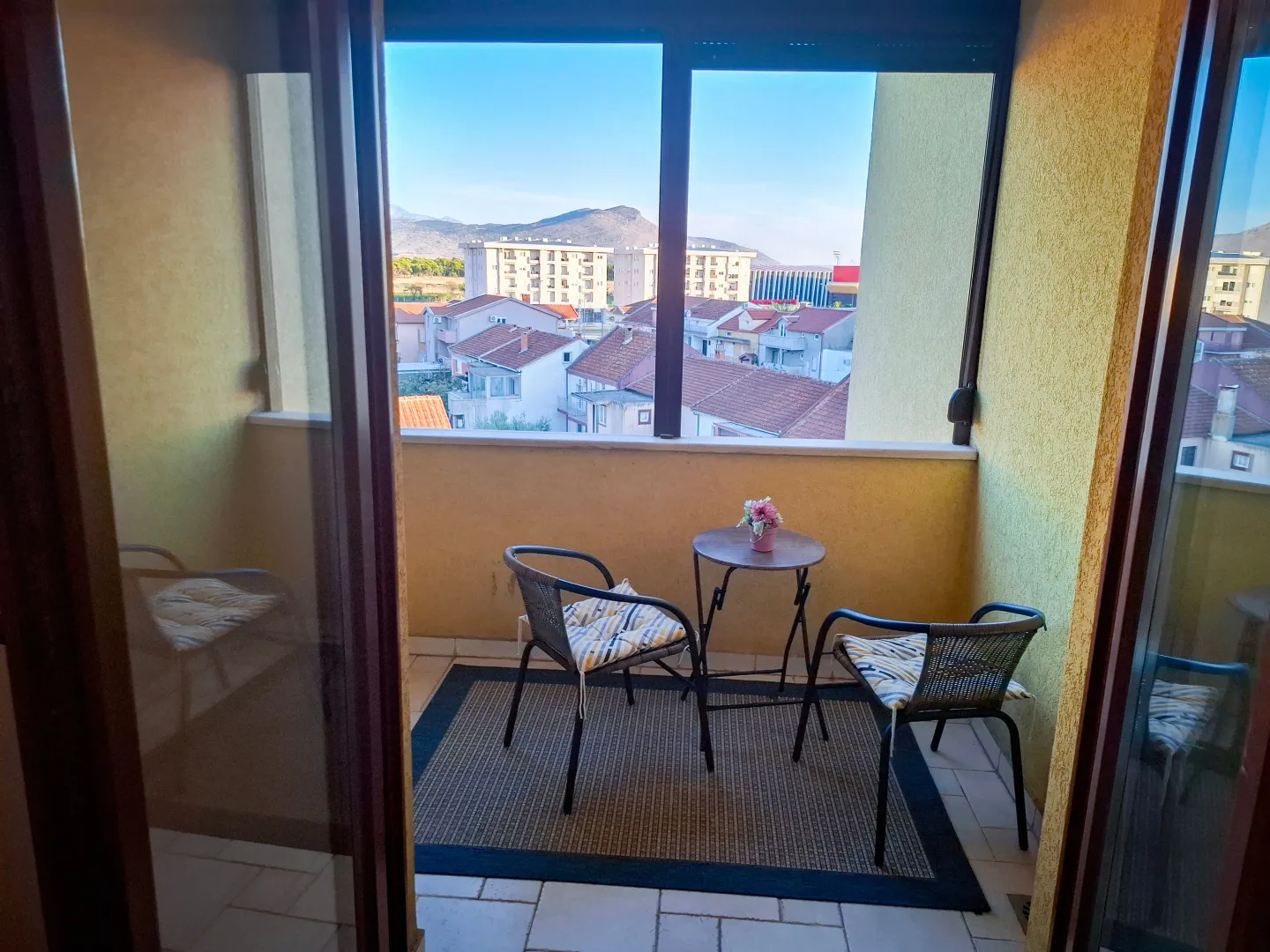 Enclosed balcony space with a small table, chairs, and a city view.