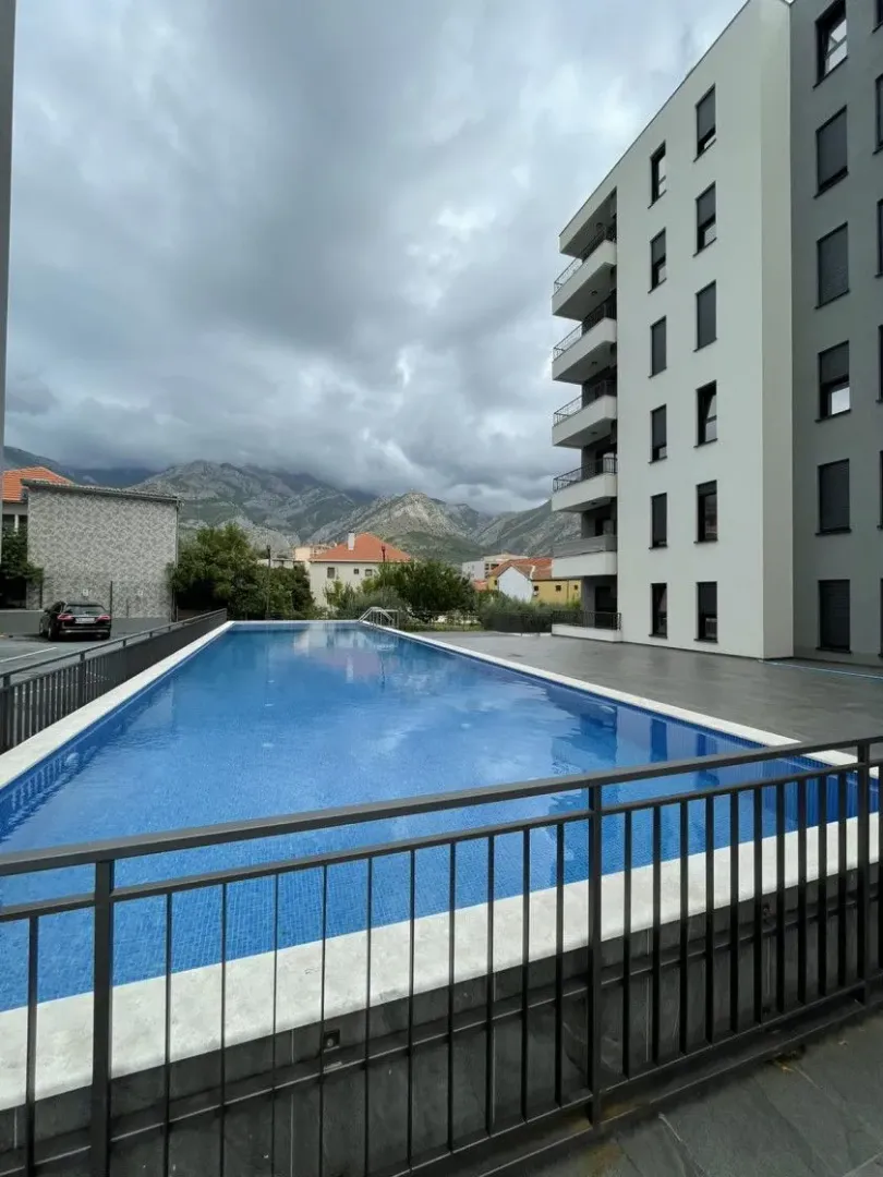 Outdoor area with a swimming pool and a view of the building and mountains in the background.