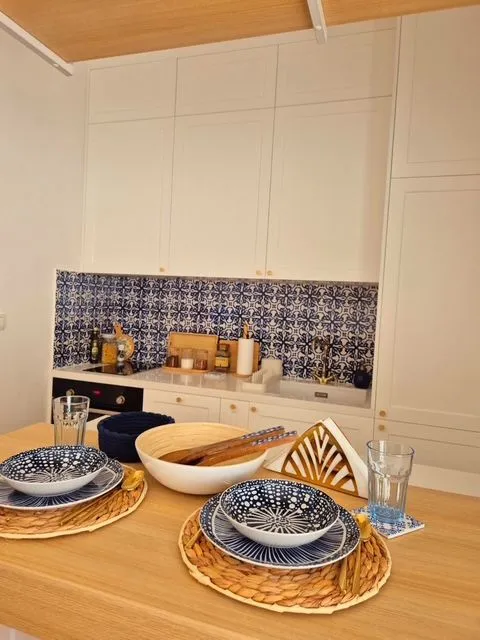 Modern kitchen with white cabinetry and a dining table in the foreground.
