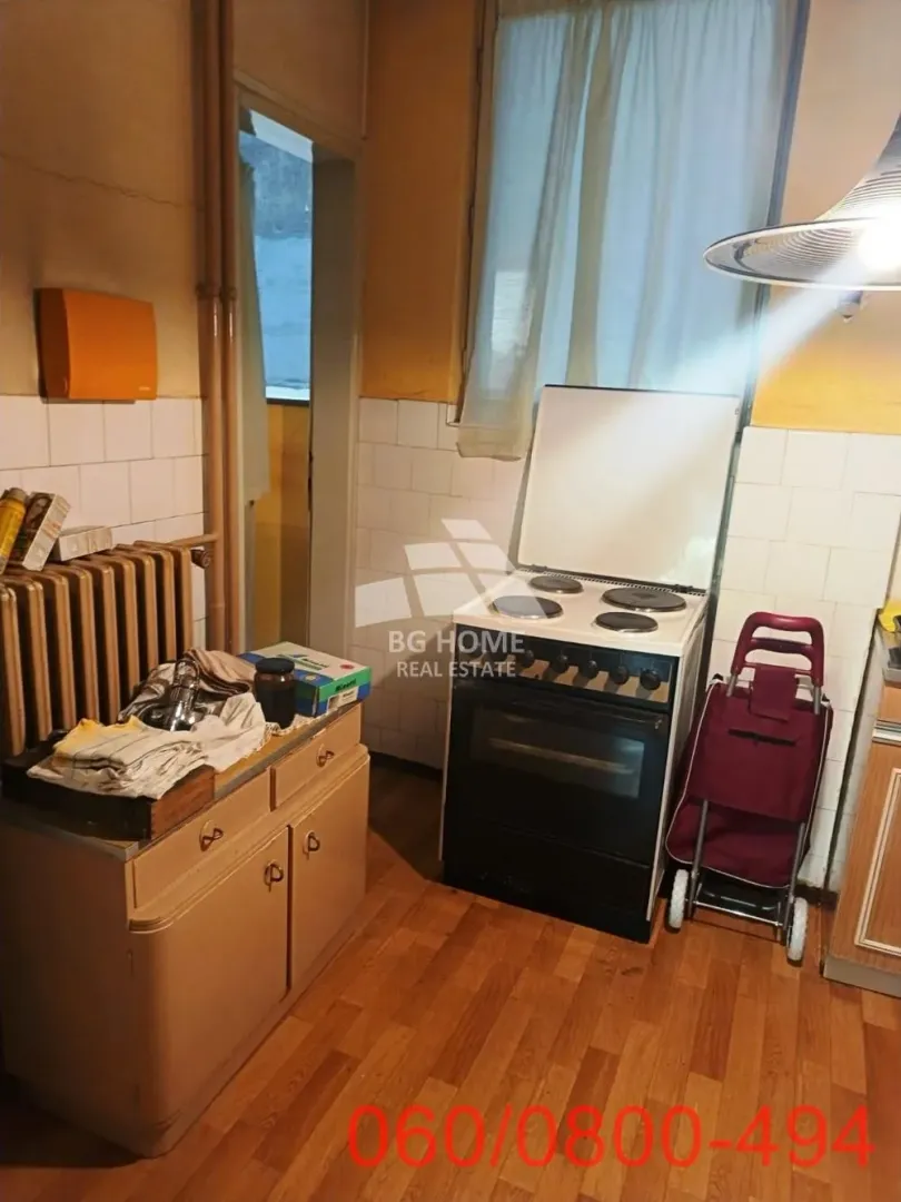 Starija kuhinja sa šporetom, elementima i radijatorom.