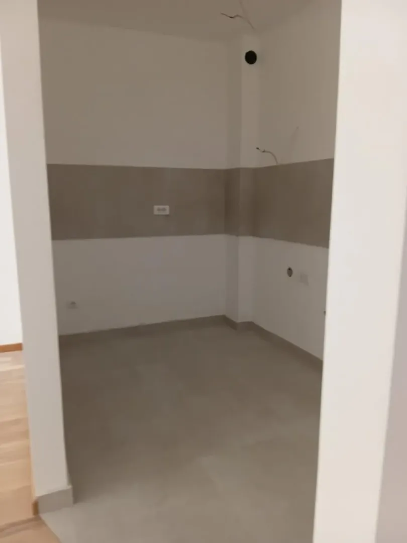 Prazna neopremljena prostorija sa pločicama na podu i zidovima u završnoj obradi.