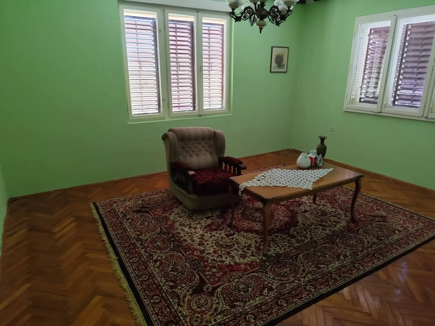 Dnevna soba sa foteljom, stočićem i tepihom na podu.