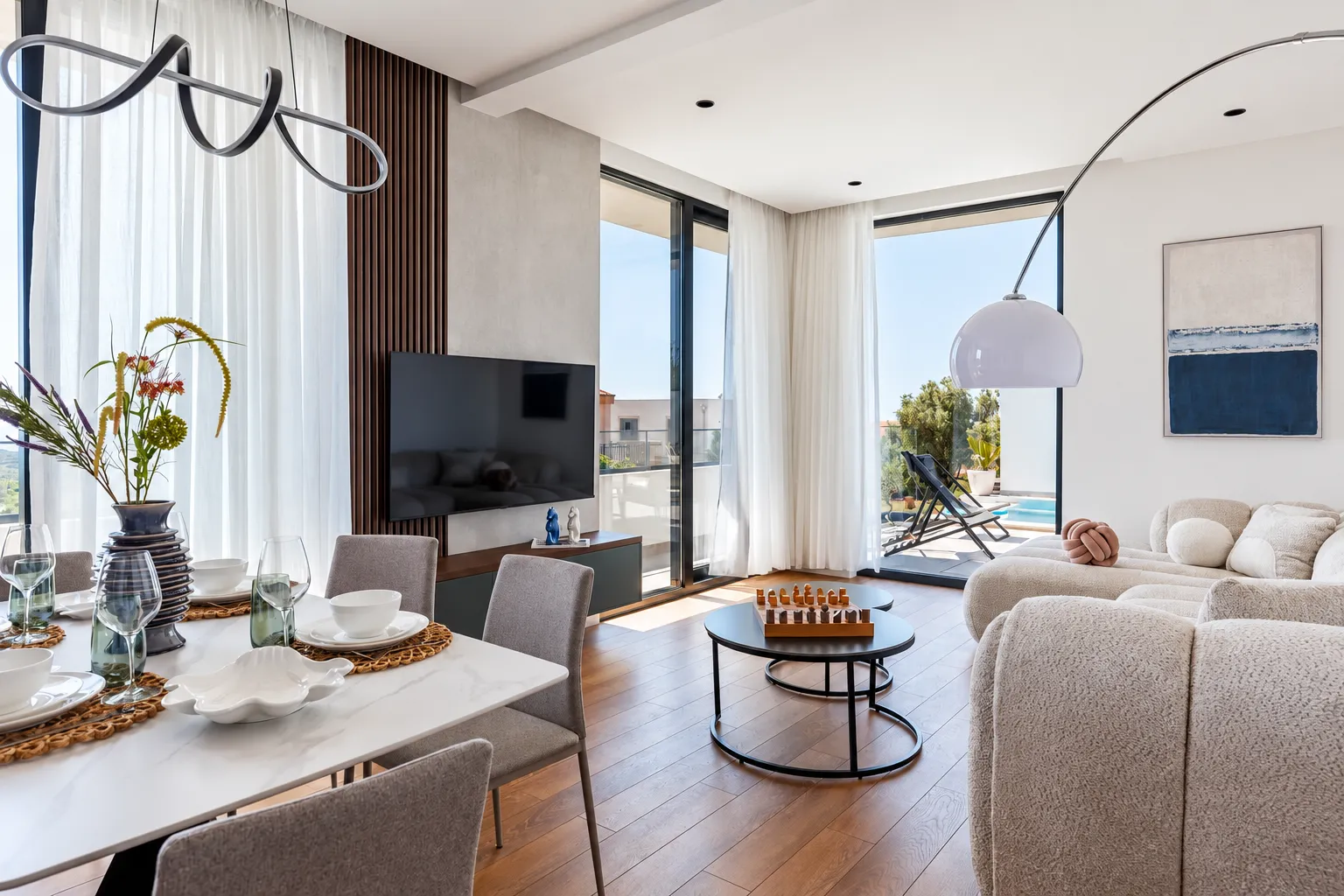 Modern living room with dining area and access to the terrace with a swimming pool.