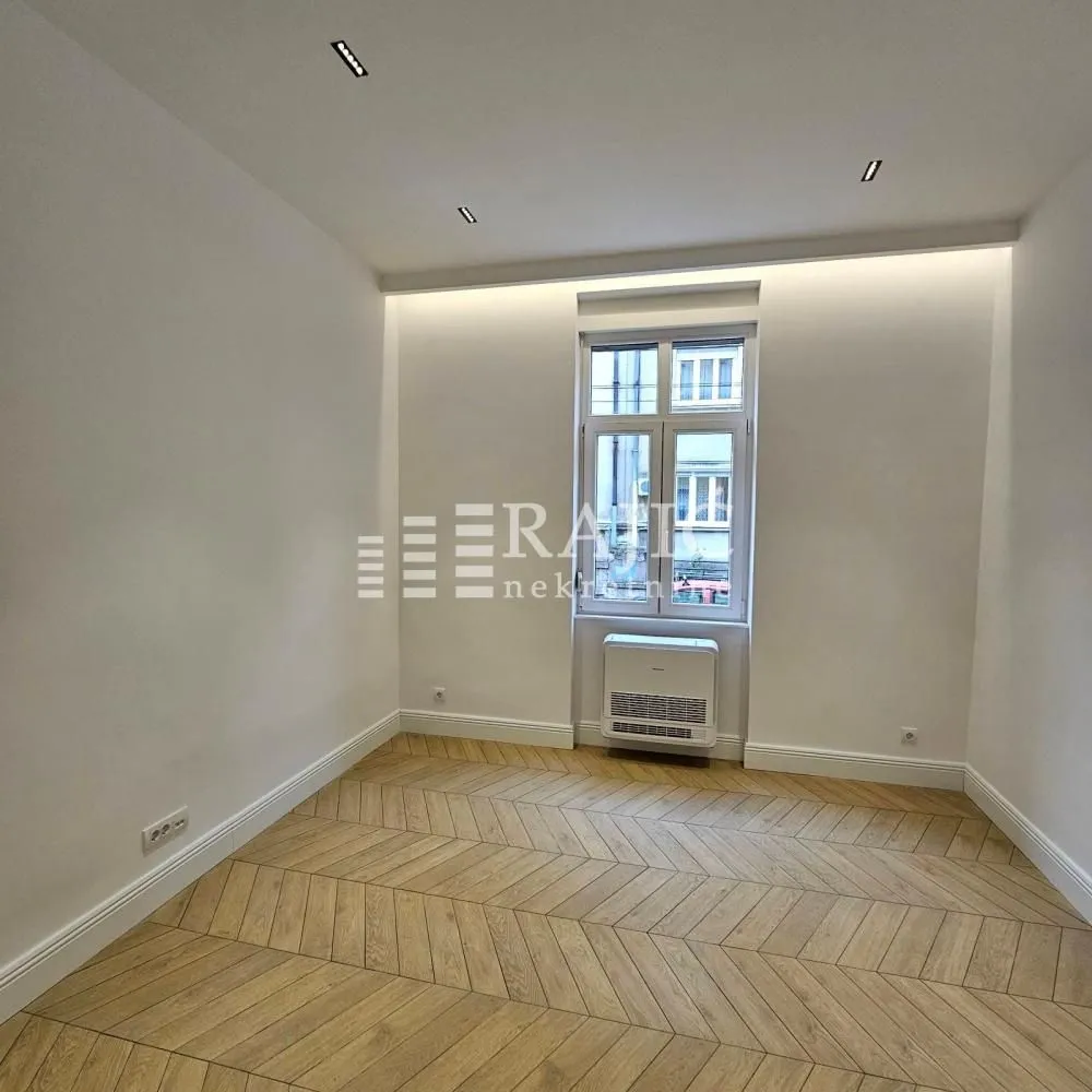 Empty room with light parquet flooring and a window.