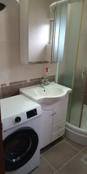 Bathroom equipped with a sink, shower cabin, and washing machine. - image 5