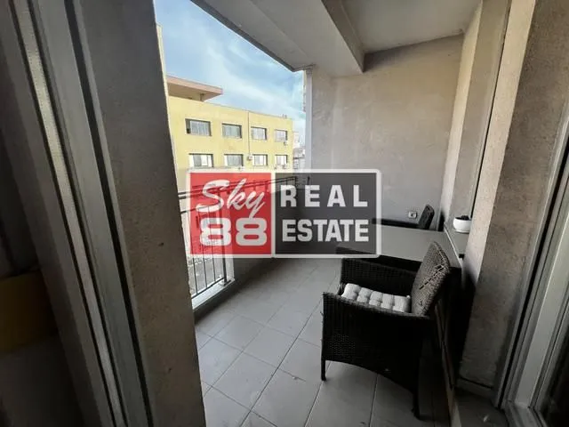 Natkriveni balkon sa garniturom za sedenje i pogledom na grad.