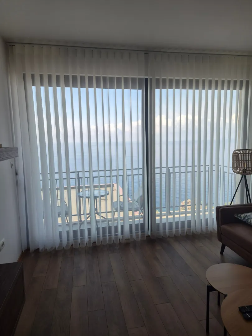 Living room with a sea view through large glass balcony doors.