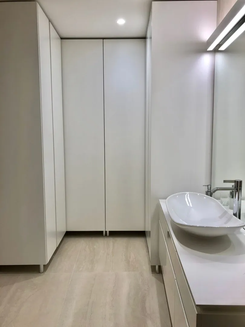 Moderno kupatilo sa bijelim ormarićima i elegantnim lavaboom.