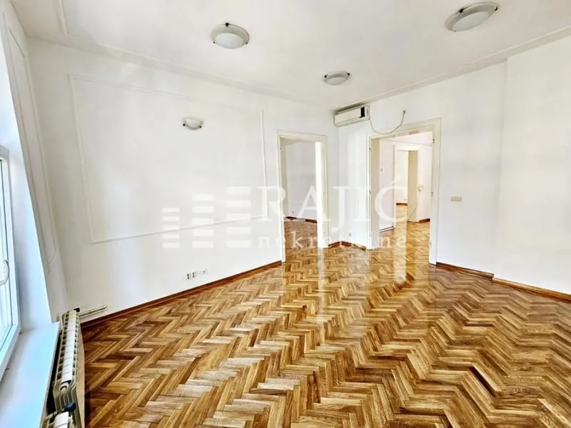 Empty living room with parquet flooring and white walls.