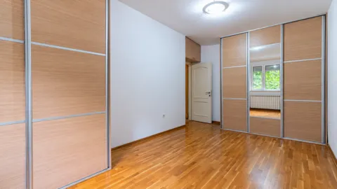Prazna spavaća soba sa velikim ugradnim plakarima i drvenim podom. - image 6