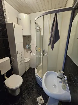 Small bathroom with a shower cabin, sink, toilet, and storage cabinet. - image 9
